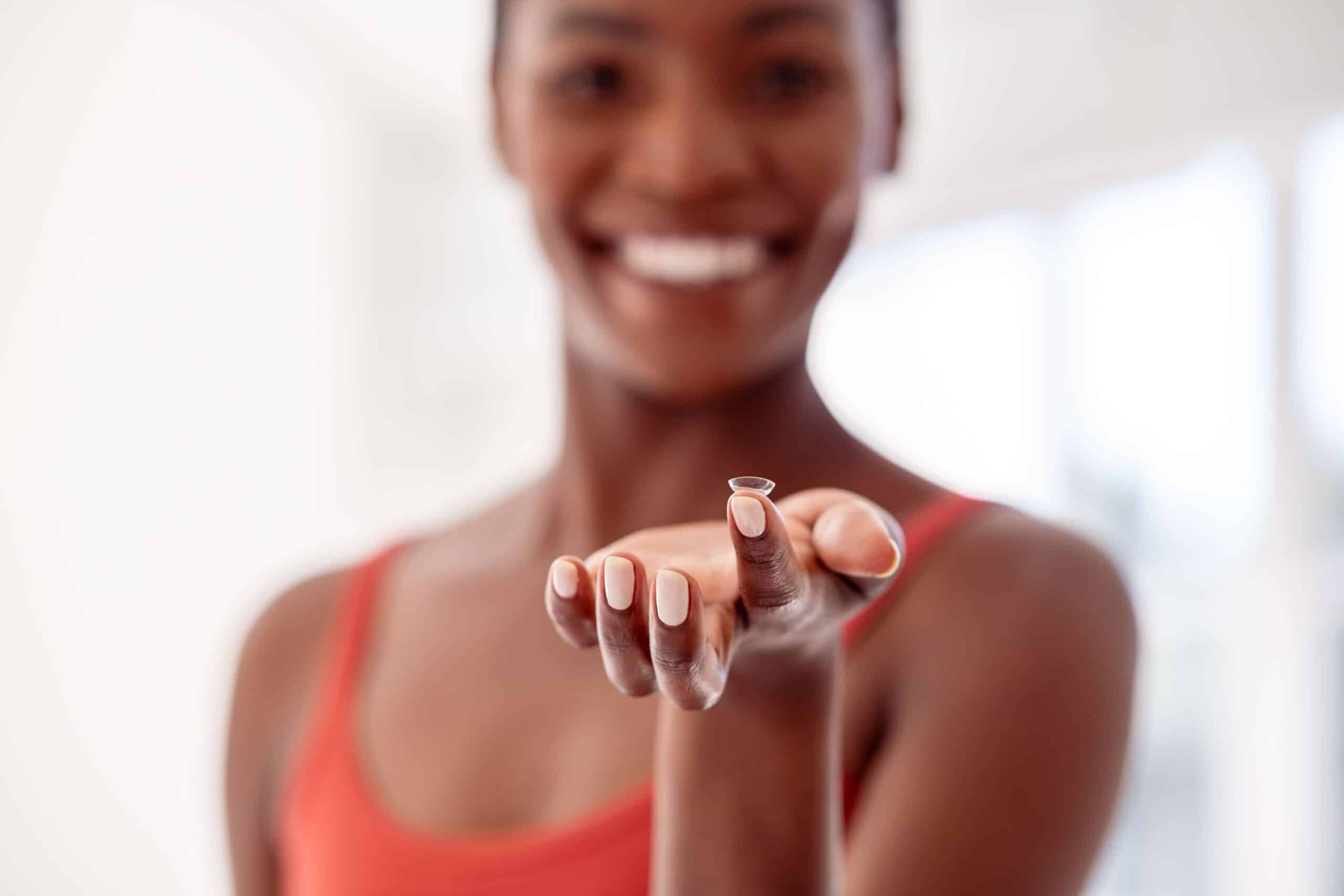 Woman holding a contact lens on her fingertip